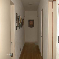 The hallway down the T. Dave's office is to the left of the pic. On the left, a spare BR half-way down and our BR at the end. On the right, the front bath, then a closet, then Vi's studio. A painting from Vi's vagina series is at the far end; mostly family pics on the left wall.